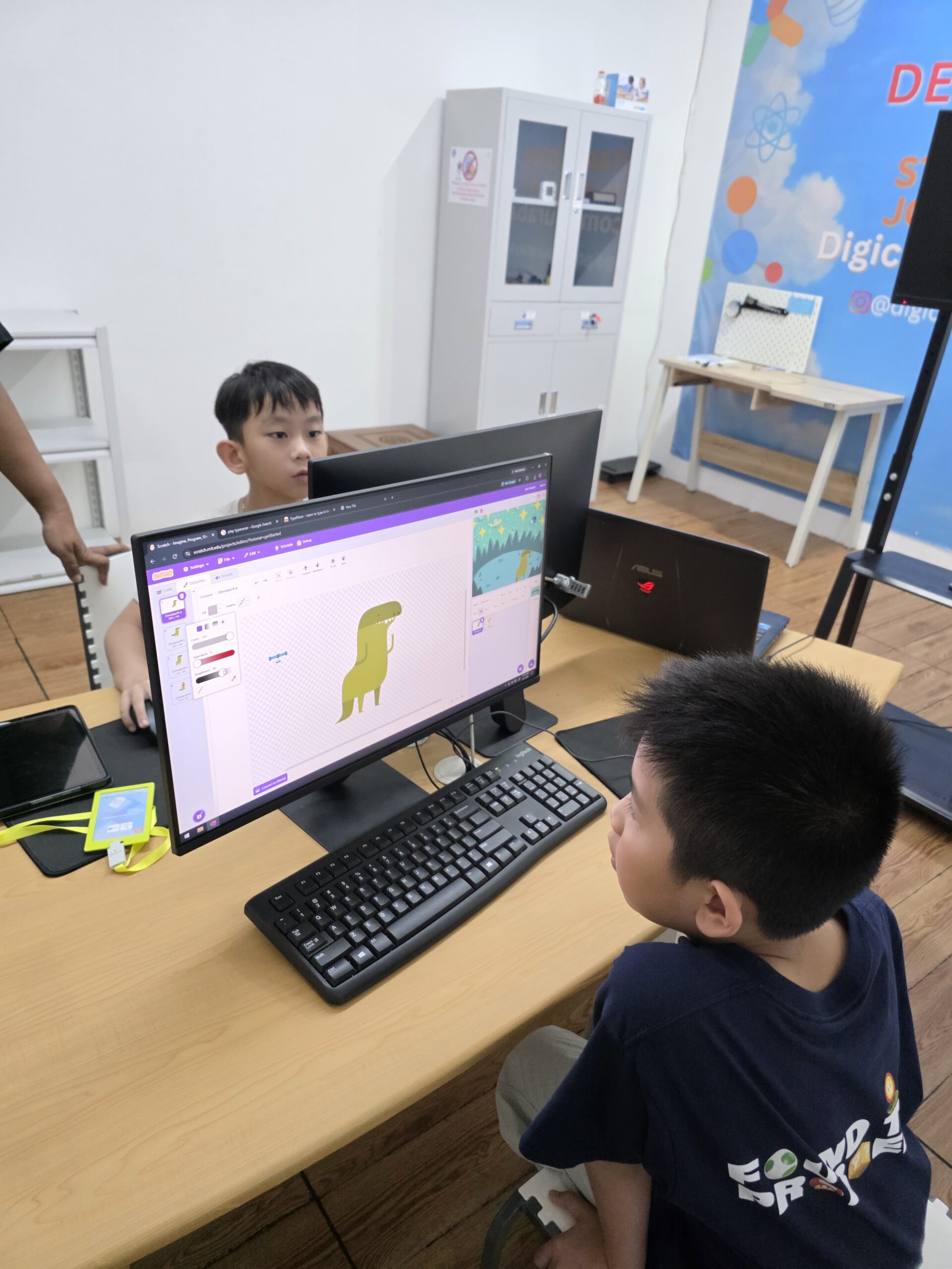 Children creating a dinosaur illustration in Scratch at Digicomp.